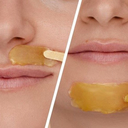 Мастер наносит воск для депиляции на чувствительную зону лица